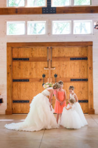 flower girls and bride next to wooden door