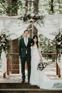 two people under white draped arbor and florals from Fox and Fern florist from Chattanooga TN