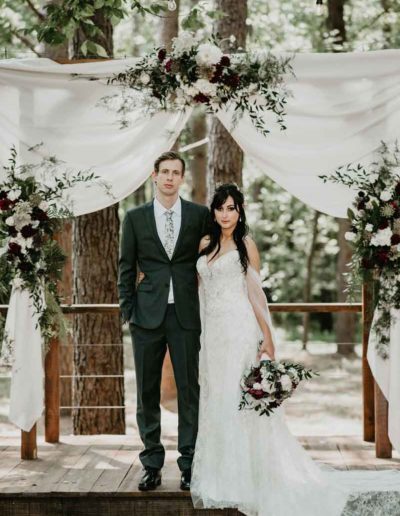 two people under white draped arbor and florals from Fox and Fern florist from Chattanooga TN